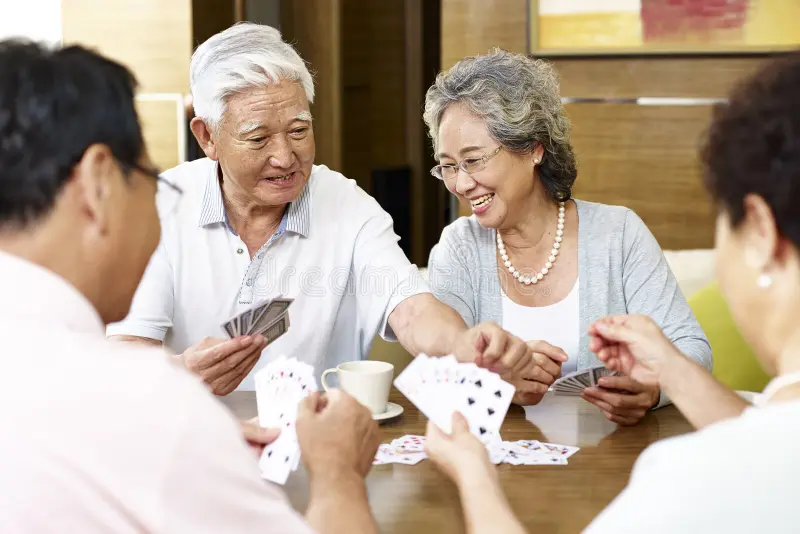 senior asian people playing cards tow couples together 82276478
